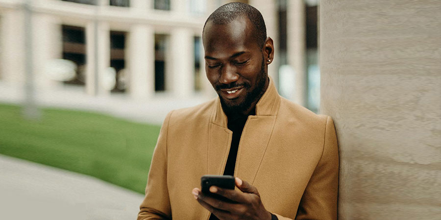 a black man smiling while using his smartphone