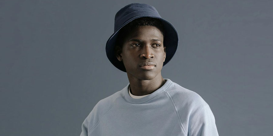 a black man wearing a bucket hat and a sweater